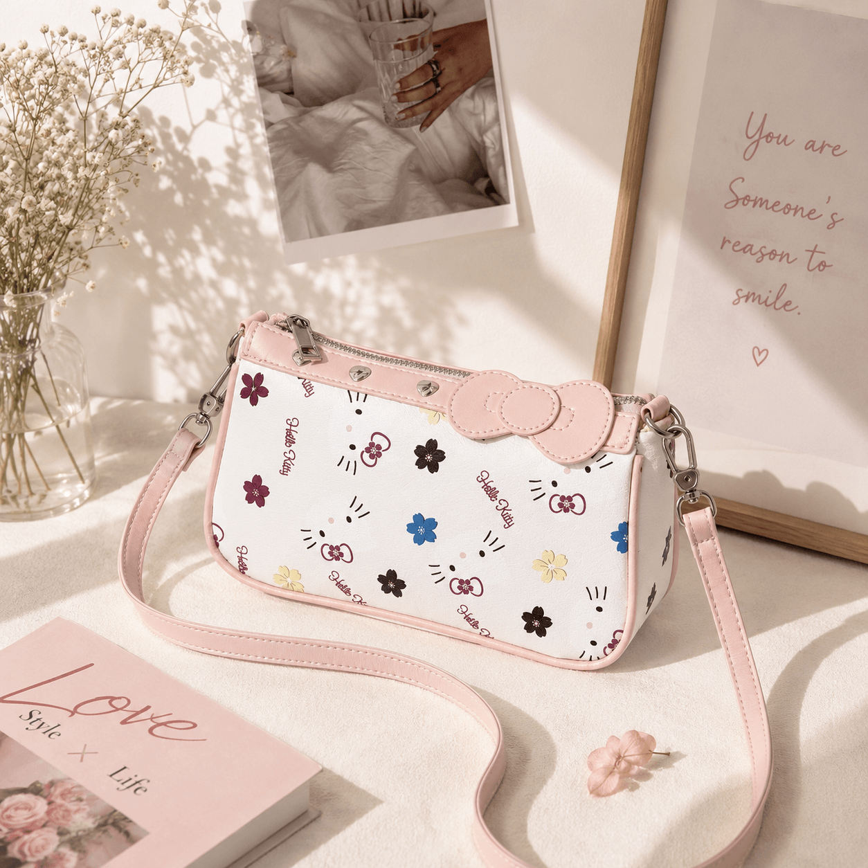 Pink floral bow crossbody shoulder bag with a white faux leather body, blush pink trim, adjustable shoulder strap, and elegant floral print, displayed in a soft pastel aesthetic setting.